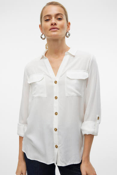 Chemisier blanc à manches longues de Vero Moda, avec poches poitrine et boutons marron.