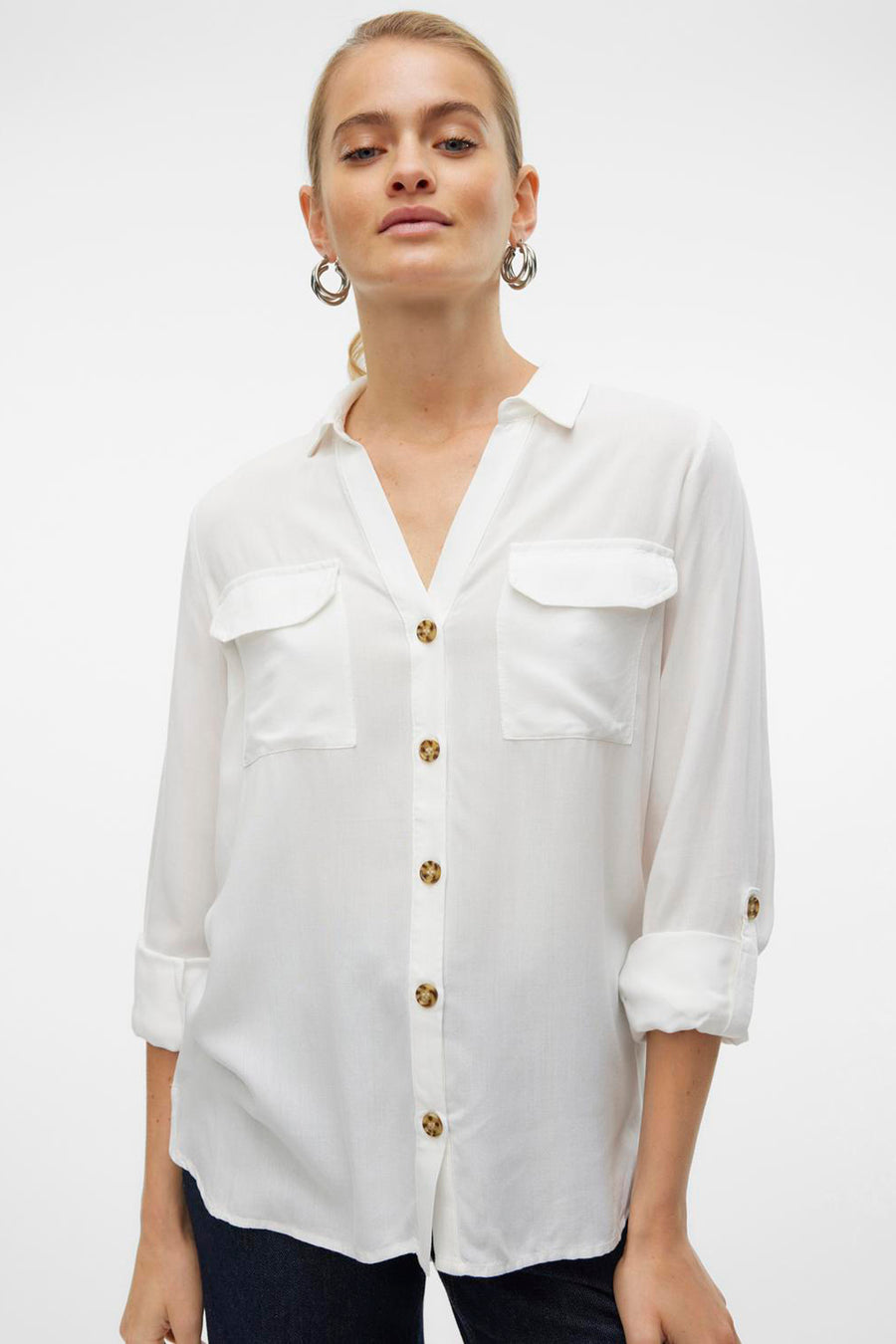 Chemisier blanc à manches longues de Vero Moda, avec poches poitrine et boutons marron.