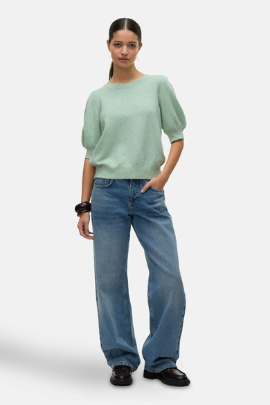 Pull vert à col rond de Vero Moda, porté avec un jean bleu ample et des mocassins noirs.