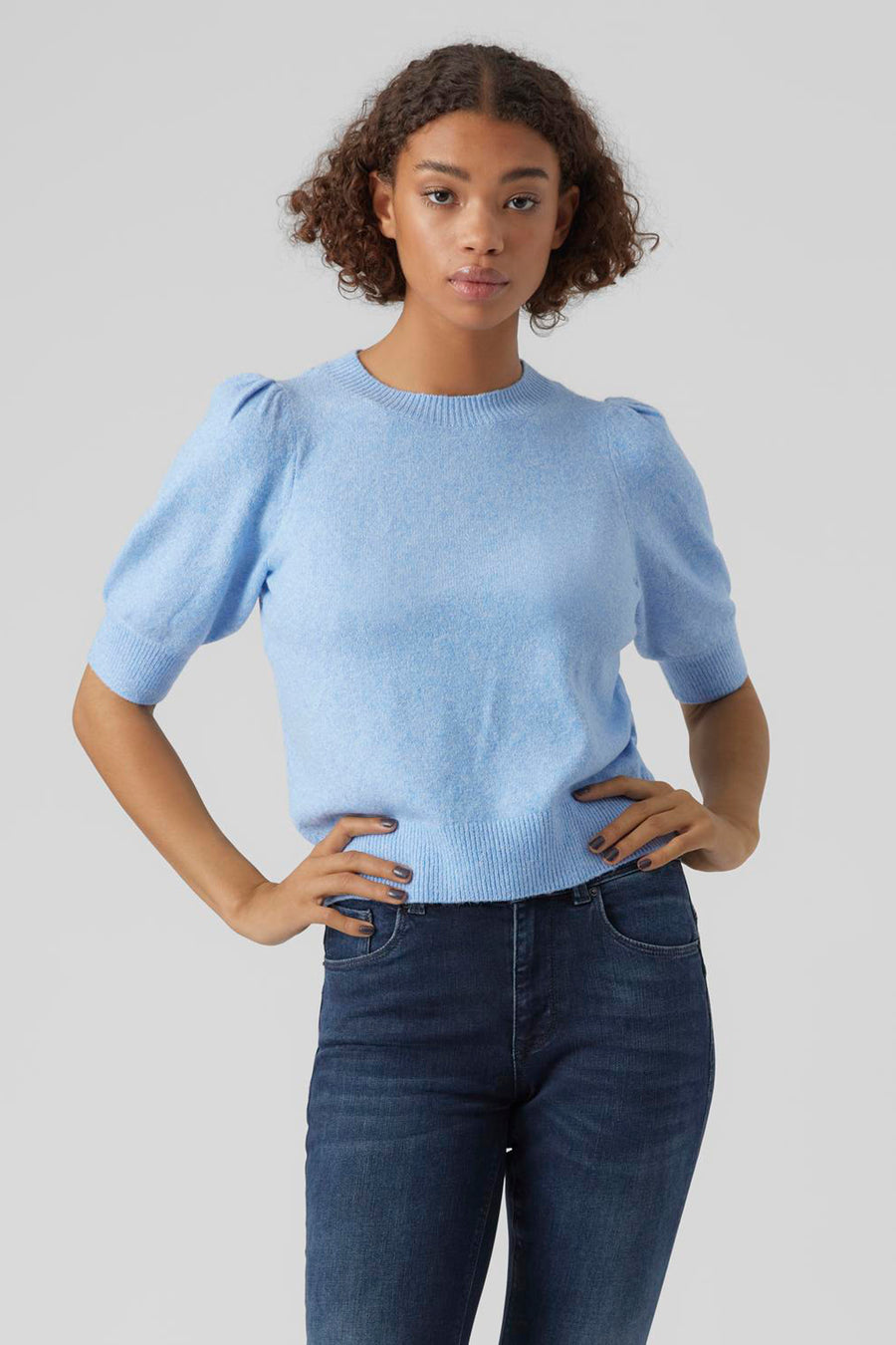 Pull bleu clair en maille de Vero Moda, avec manches courtes bouffantes et porté avec un jean.
