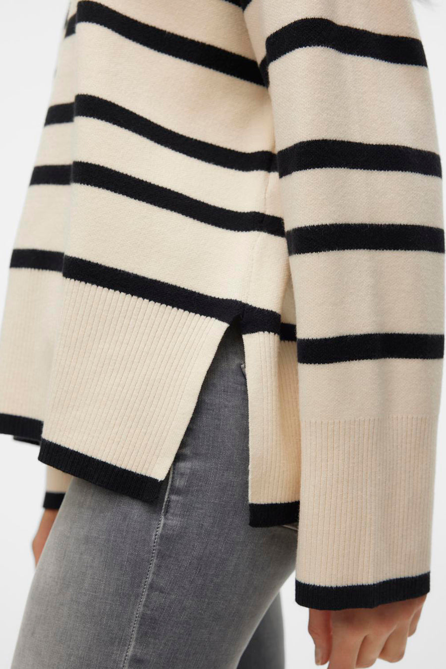 Beige trui met zwarte strepen van VERO MODA®, met zijsplitten, gedragen met een grijze jeans.
