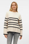 Beige trui met zwarte strepen van VERO MODA, gedragen met een grijze jeans en gouden oorbellen.
