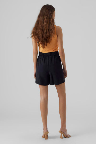 Short noir de VERO MODA, porté avec un débardeur orange et des mules à talons couleur chair.