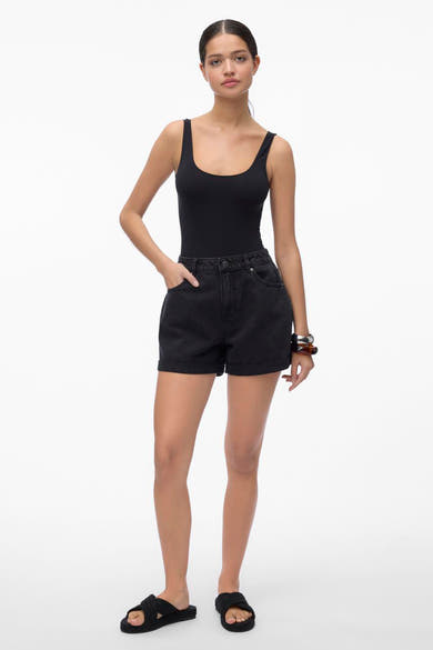 Short noir de VERO MODA, porté avec un body noir et des sandales tissées.