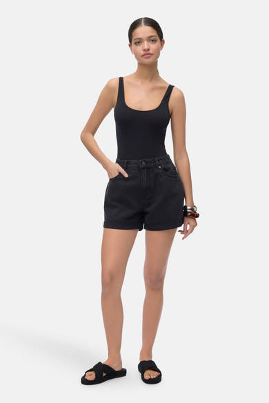 Korte zwarte short van VERO MODA, gedragen met een zwarte bodysuit en zwarte sandalen.