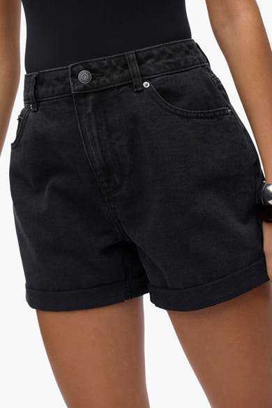 Korte zwarte short van VERO MODA, met omgeslagen zomen en voorzakken, gedragen met een zwarte body.