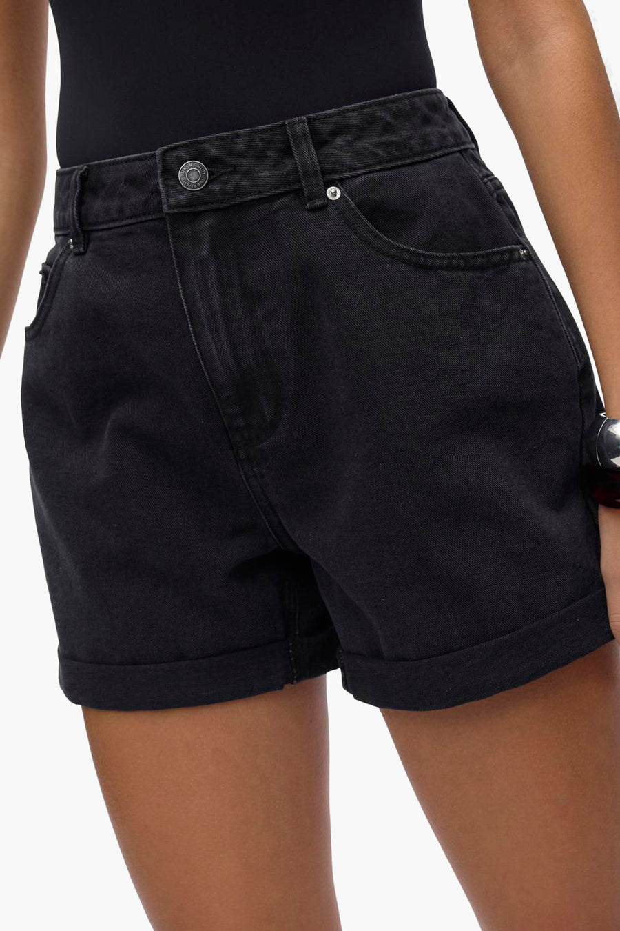 Korte zwarte short van VERO MODA, met omgeslagen zomen en voorzakken, gedragen met een zwarte body.