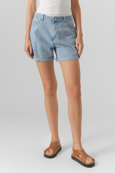Short en jean bleu de VERO MODA, porté avec un débardeur blanc et des sandales en cuir marron.