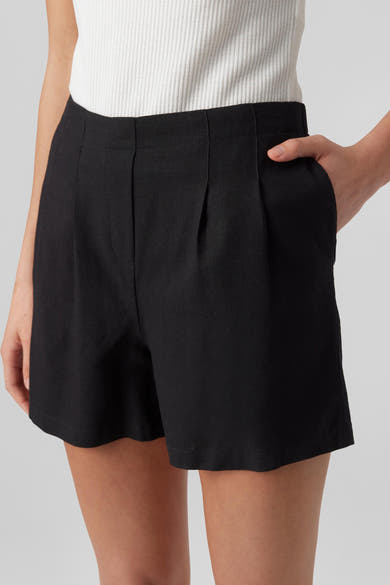 Short noir de Vero Moda, avec plis sur le devant et une personne avec une main dans une poche.