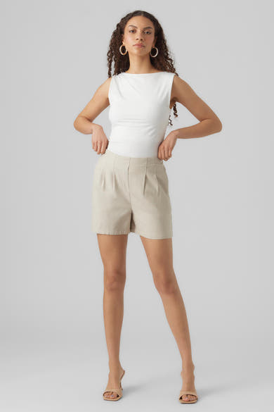 Short beige de VERO MODA, porté avec un haut blanc et des mules à talons beiges.