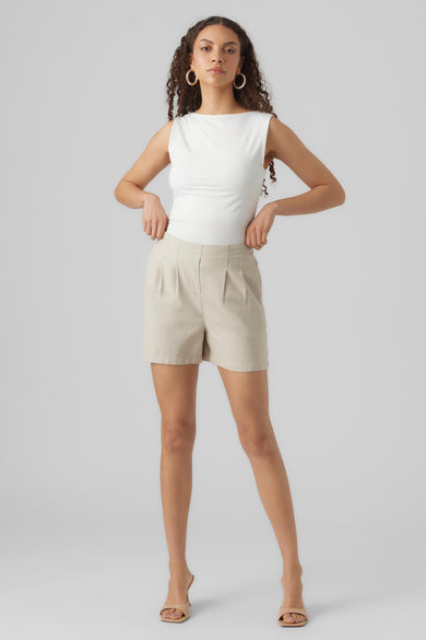 Short beige de VERO MODA, porté avec un haut blanc et des mules à talons beiges.