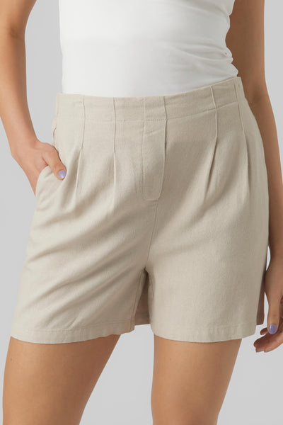 Short beige de VERO MODA avec poches, plis et ourlet cousu, porté avec un débardeur blanc.