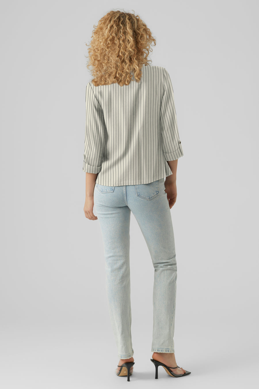 Blazer beige à rayures verticales de VERO MODA®, porté avec un jean clair et des talons aiguilles noirs.