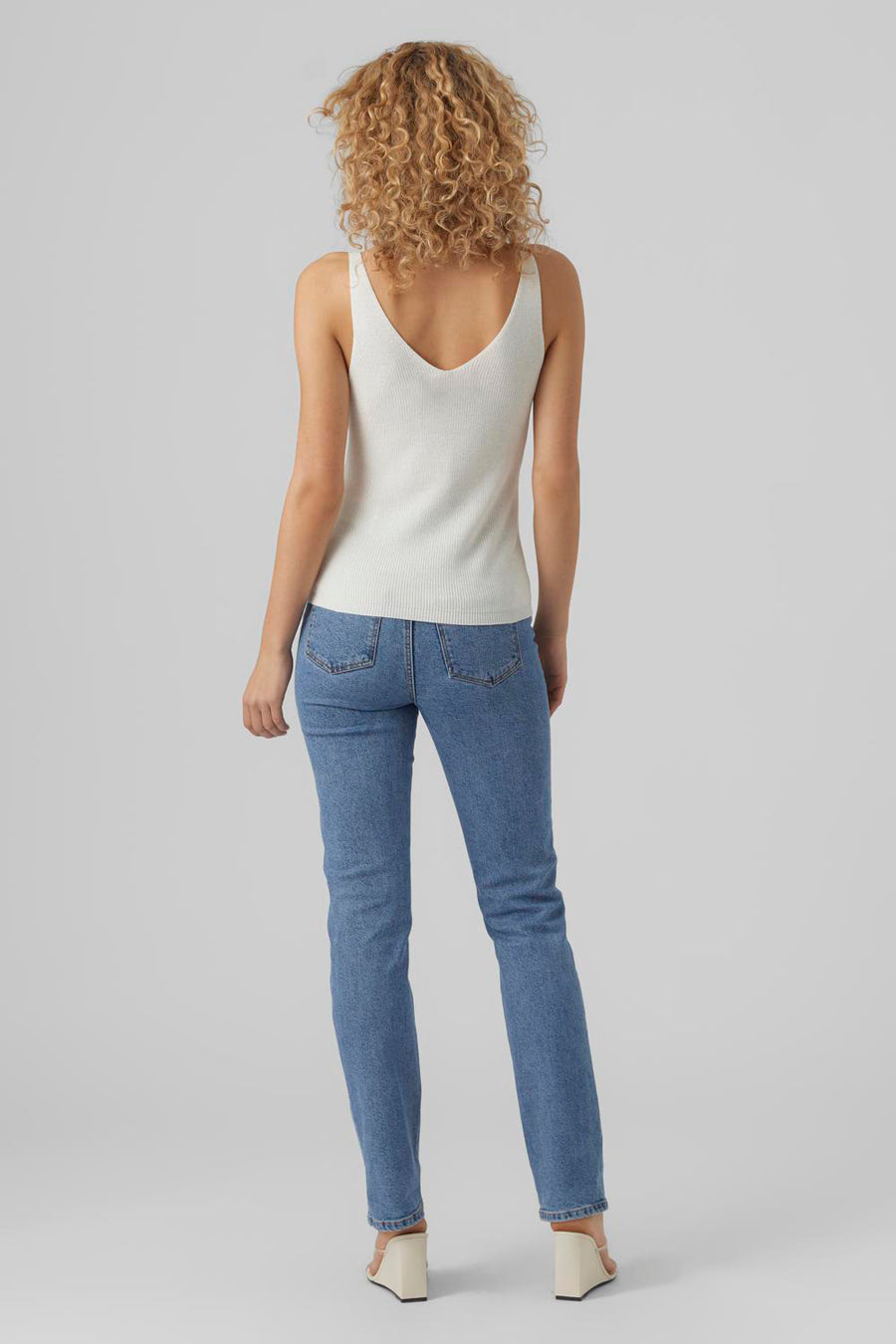 Débardeur blanc de VERO MODA, avec texture côtelée, porté avec un jean bleu et des chaussures compensées, vue arrière.