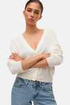 Gilet blanc en maille, de VERO MODA®, avec boutons devant et porté avec un jean bleu clair.