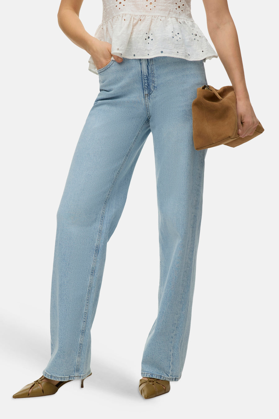 Jean droit bleu de VERO MODA®, porté avec un haut blanc ajouré et des chaussures à talons en cuir.
