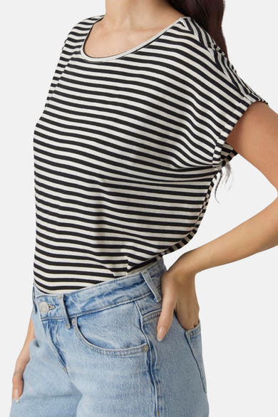 Zwart gestreept T-shirt van VERO MODA®, gedragen met een lichtblauwe jeans en één hand in de zak.