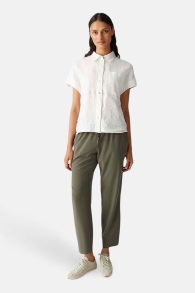 Kaki kleurige broek van OPUS, gedragen met een witte blouse en beige sneakers.