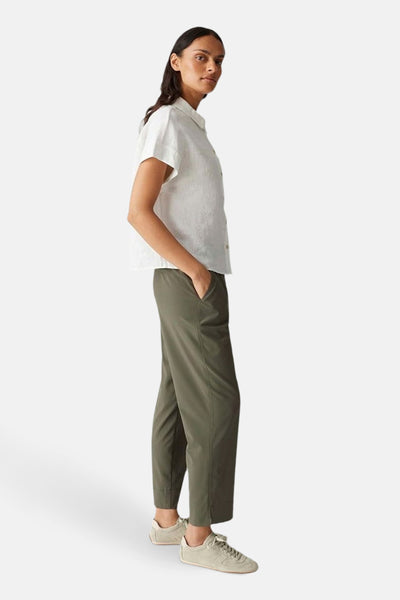 Pantalon coloré kaki de OPUS, avec une poche et une fente latérale, porté avec un chemisier blanc et des baskets.