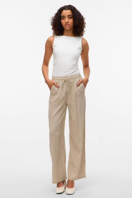 Pantalon beige à rayures verticales de Vero Moda, porté avec un haut blanc et des chaussures plates.