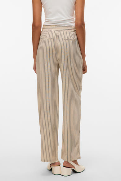 Pantalon beige rayé de VERO MODA, avec une taille élastique et des poches arrière, porté avec un haut blanc et des chaussures à talons clairs.