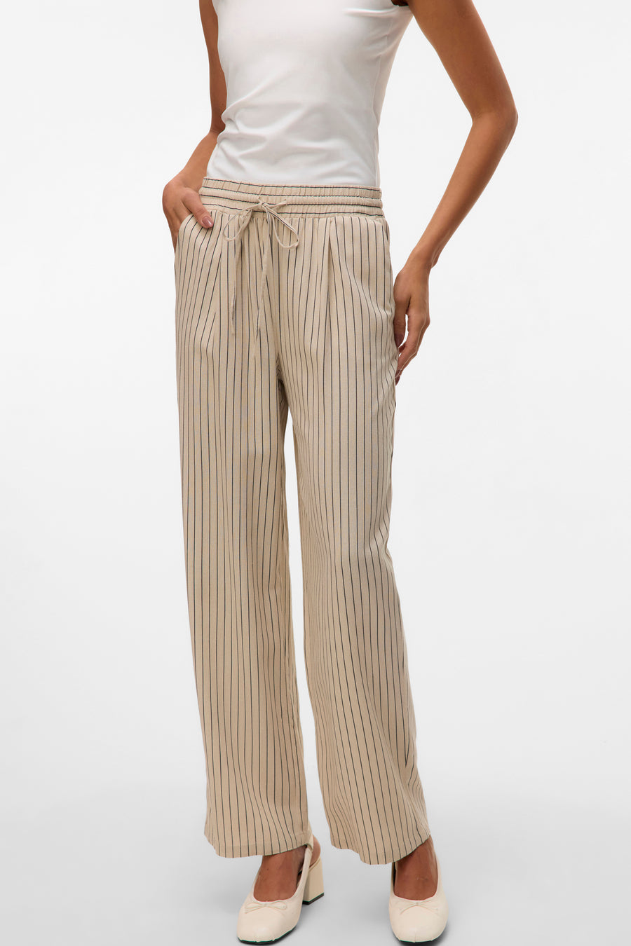 Pantalon beige à rayures fines de VERO MODA, avec cordon de serrage à la taille et chaussures ivoire.
