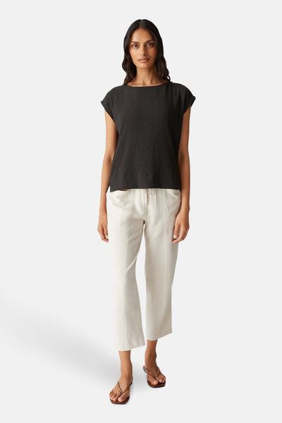 Bruin mouwloos blouse van OPUS, gedragen met een crèmekleurige broek met trekkoord en sandalen.