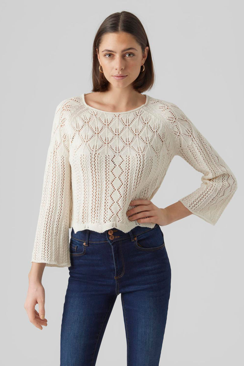 Pull beige en maille ajourée de VERO MODA, porté avec un jean taille haute bleu marine.