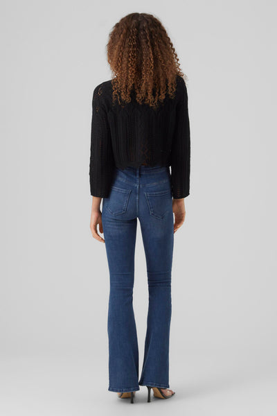 Pull noir à mailles ajourées de VERO MODA, porté avec un jean taille haute évasé et des talons aiguilles.