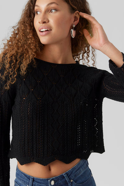 Pull noir à col rond de VERO MODA®, en maille ajourée, porté avec un jean taille haute.