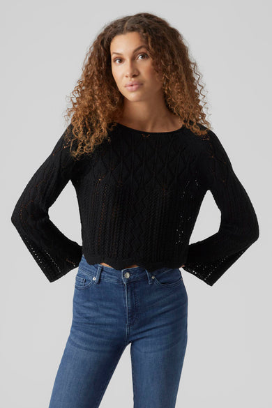 Pull noir en maille ajourée de VERO MODA, avec manches longues évasées et porté avec un jean taille haute.

