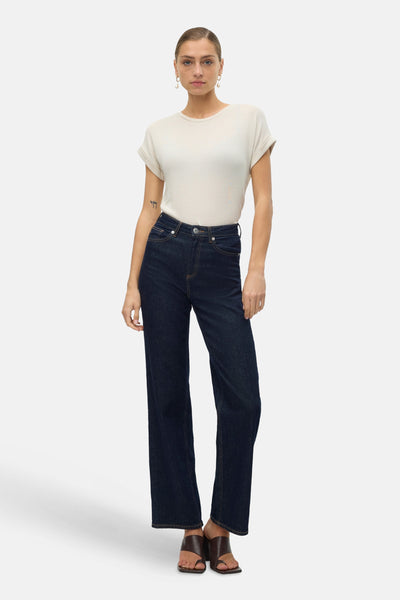 T-shirt beige à manches courtes de VERO MODA, porté avec un jean taille haute bleu marine et des sandales marron.
