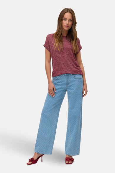 T-shirt rouge à manches courtes de Vero Moda, porté avec un jean bleu à motifs et des mules rouges.
