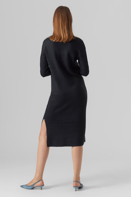 Robe midi noire de VERO MODA, avec une fente latérale et portée avec des escarpins bleus.
