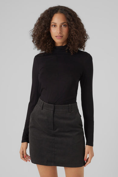 Zwarte top met lange mouwen van Vero Moda, gedragen met een corduroy rok en hoge bruine laarzen.