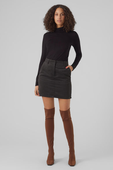 Haut à manches longues noir de Vero Moda, porté avec une jupe en velours côtelé et des bottes hautes marron.
