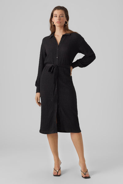 Robe midi noire par VERO MODA®, texturée avec une ceinture assortie et des sandales à talons.