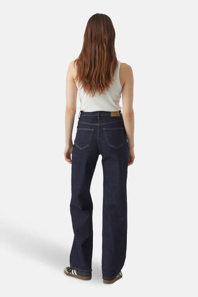 Jean large en denim bleu foncé de Vero Moda, porté avec un débardeur blanc et des baskets noires.