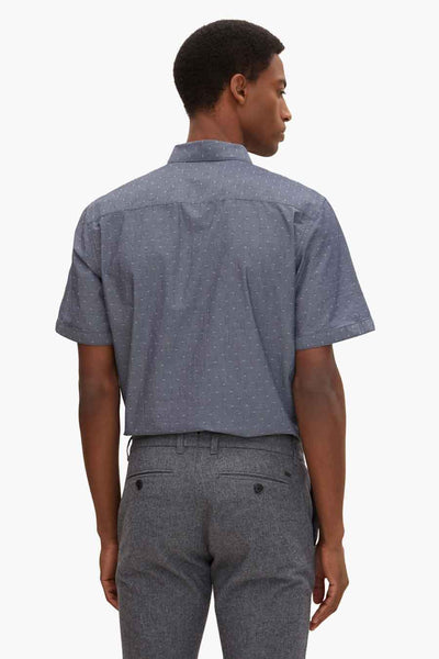 Blue short-sleeve shirt with white micro-pattern, back view, worn with gray textured trousers