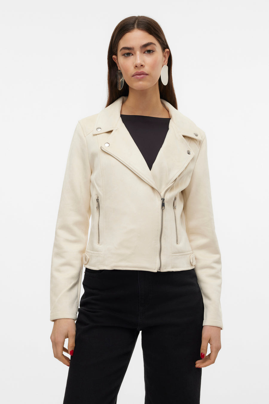 Veste en similicuir beige de Vero Moda, avec fermeture éclair asymétrique et porté sur un haut noir et un pantalon noir.
