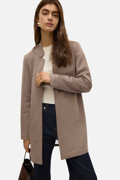 Veste longue marron de VERO MODA avec poches plaquées, portée sur un pull blanc et un jean.