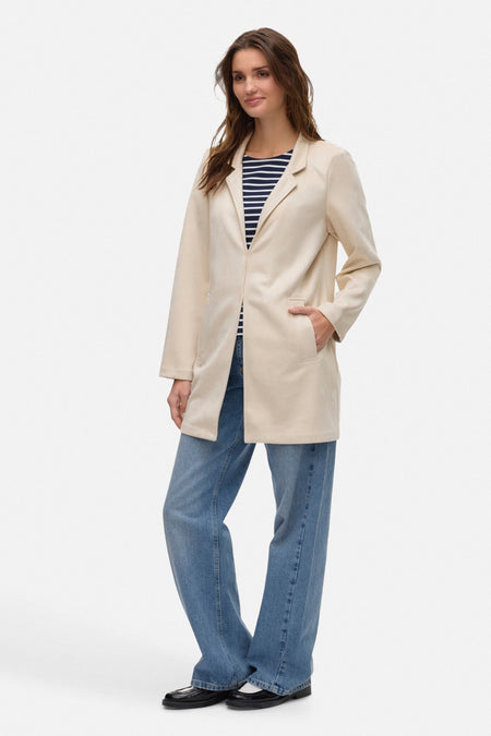Ecru lange jas van VERO MODA, gedragen over een marineblauw en wit gestreept T-shirt en een wijde blauwe jeans.