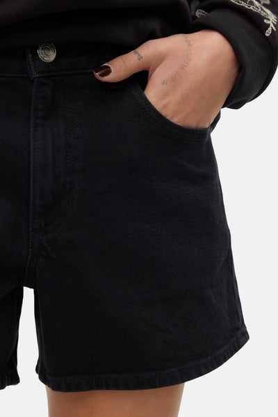 Short noir en denim de VERO MODA, avec détail de poche et inscription sur la main.