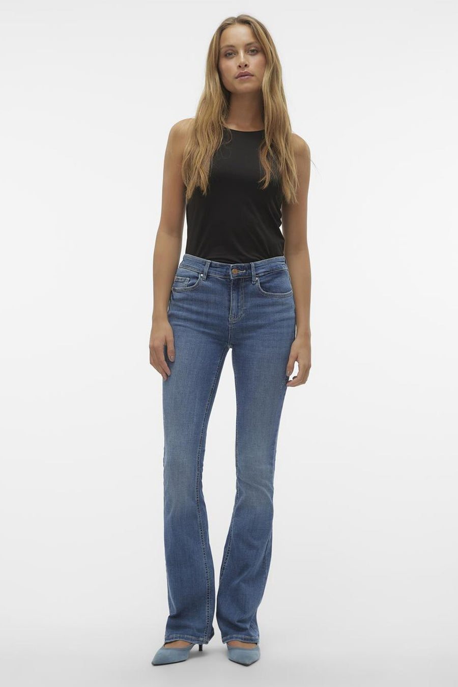 Jean évasé bleu moyen de Vero Moda, porté avec un haut noir et des chaussures pointues bleues.