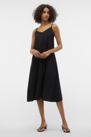 Zwarte midi-jurk van VERO MODA®, losse pasvorm met dunne bandjes en sandalen met hak.