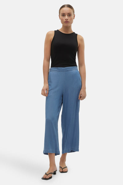 Pantalon bleu denim par VERO MODA, porté avec un débardeur noir et des sandales minimalistes.
