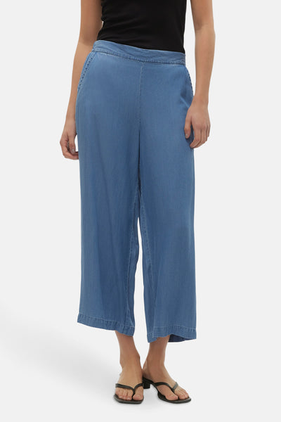 Pantalon ample en denim bleu moyen de VERO MODA, porté avec un haut noir et des sandales à lanières.