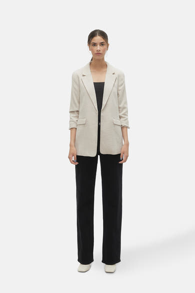 Blazer écru de VERO MODA, porté avec un haut noir et un pantalon noir ample.