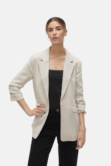 Blazer écru de VERO MODA® porté avec un haut noir et un pantalon noir.