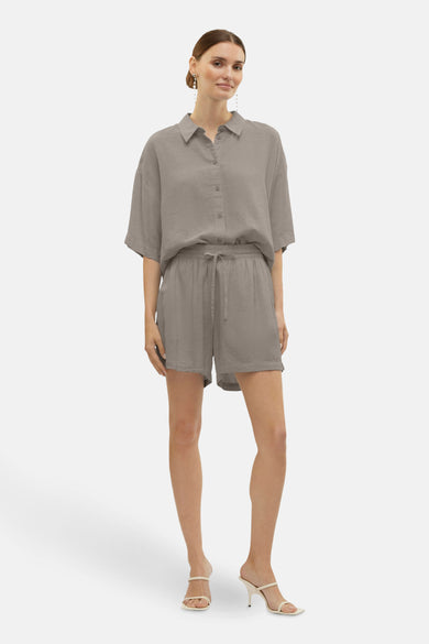 Short beige de VERO MODA, porté avec une chemise assortie et des sandales à talons.